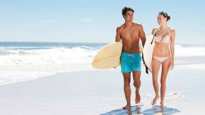 man and woman with surfboards on the beach