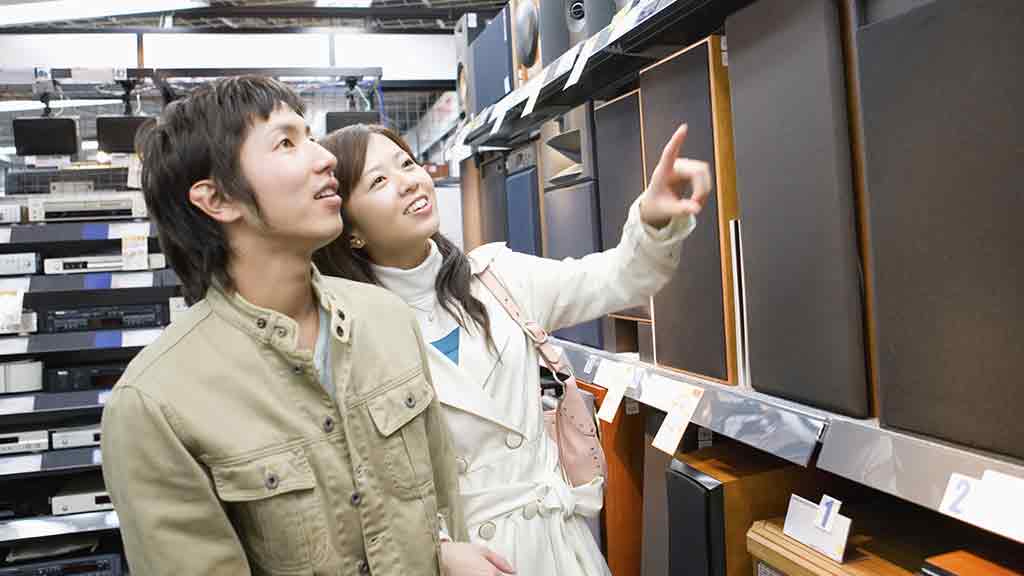 couple point at speakers in shop