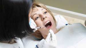 dentist performs dental work on woman in chair