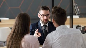 man at desk talking to two customers
