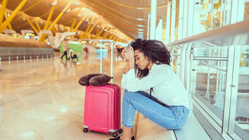woman at airport with head in hands