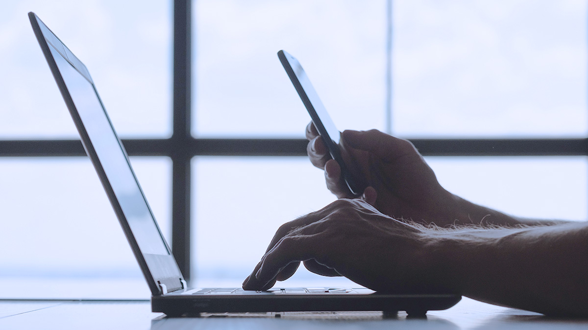 person entering two factor authentication from their smartphone on a laptop