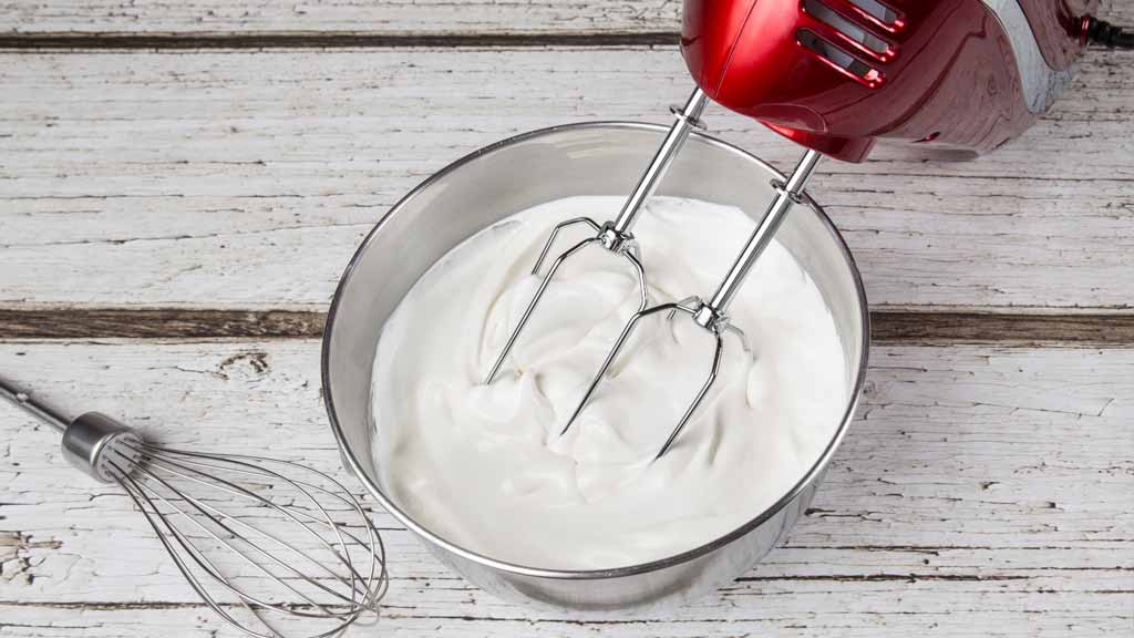 red mixer in bowl of whipped cream
