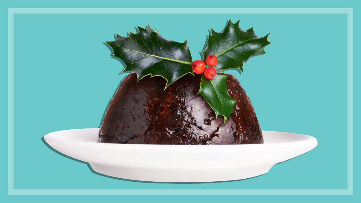 traditional Christmas pudding sitting on a white plate on a teal background