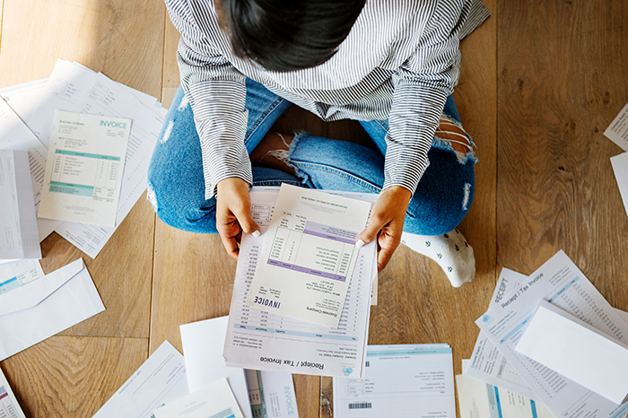 person_sitting_on_floor_looking_at_several_bills_and_invoices