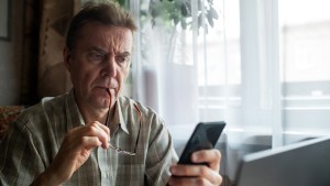 man_looking_at_phone_banking_scam_lead