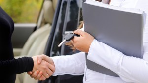 salesperson handing over keys to used car