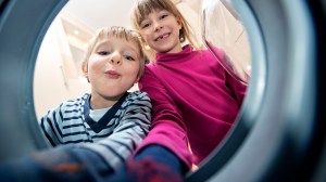 kids taking laundry out of front loader washing machine