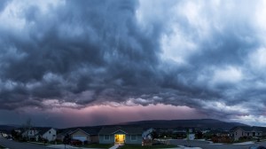 dark storm clouds over a suburb one home with its lights on